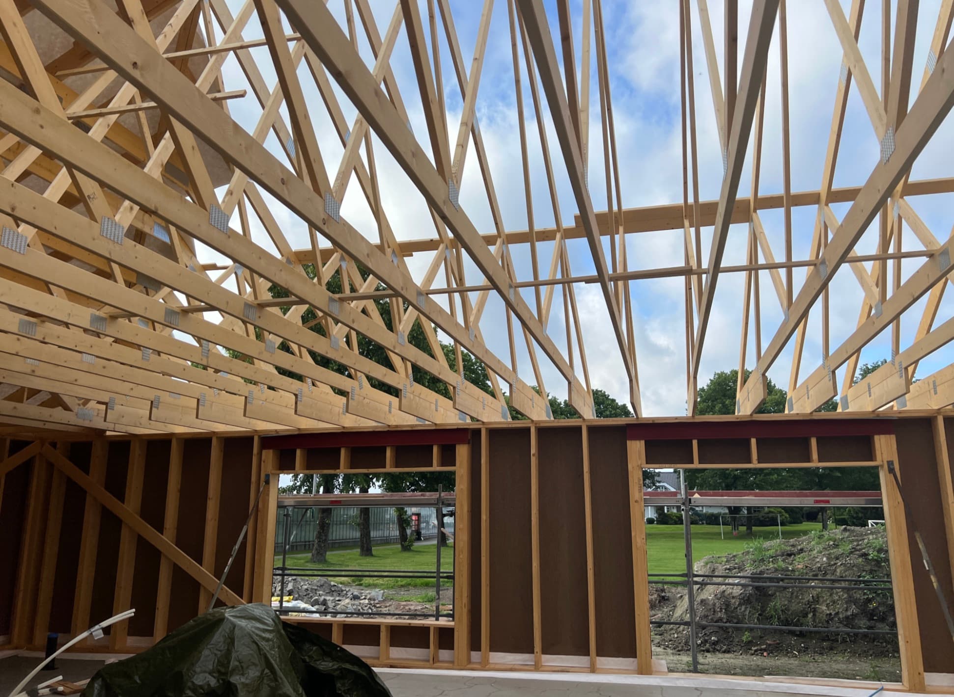 Takstoler i tre reises over et nytt hus, sett innenfra med utsikt mot hagen